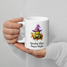 Load image into Gallery viewer, white mug with green frog on a bed of leaves and wearing a purple witch hat says spooky vibes sugar highs. Microwave and dishwasher safe
